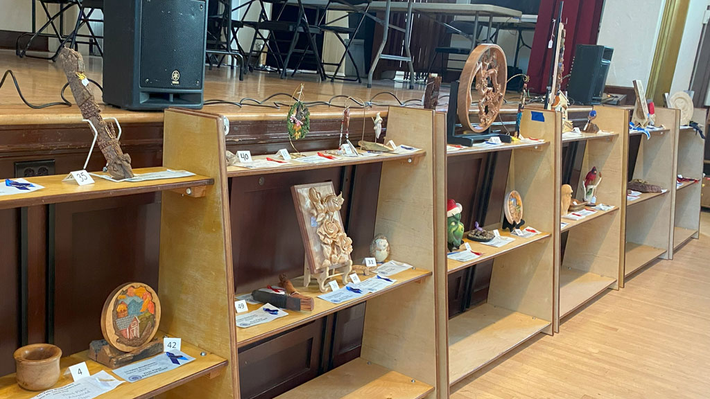Six shelves full of woodcarvings that were submitted for the competition.