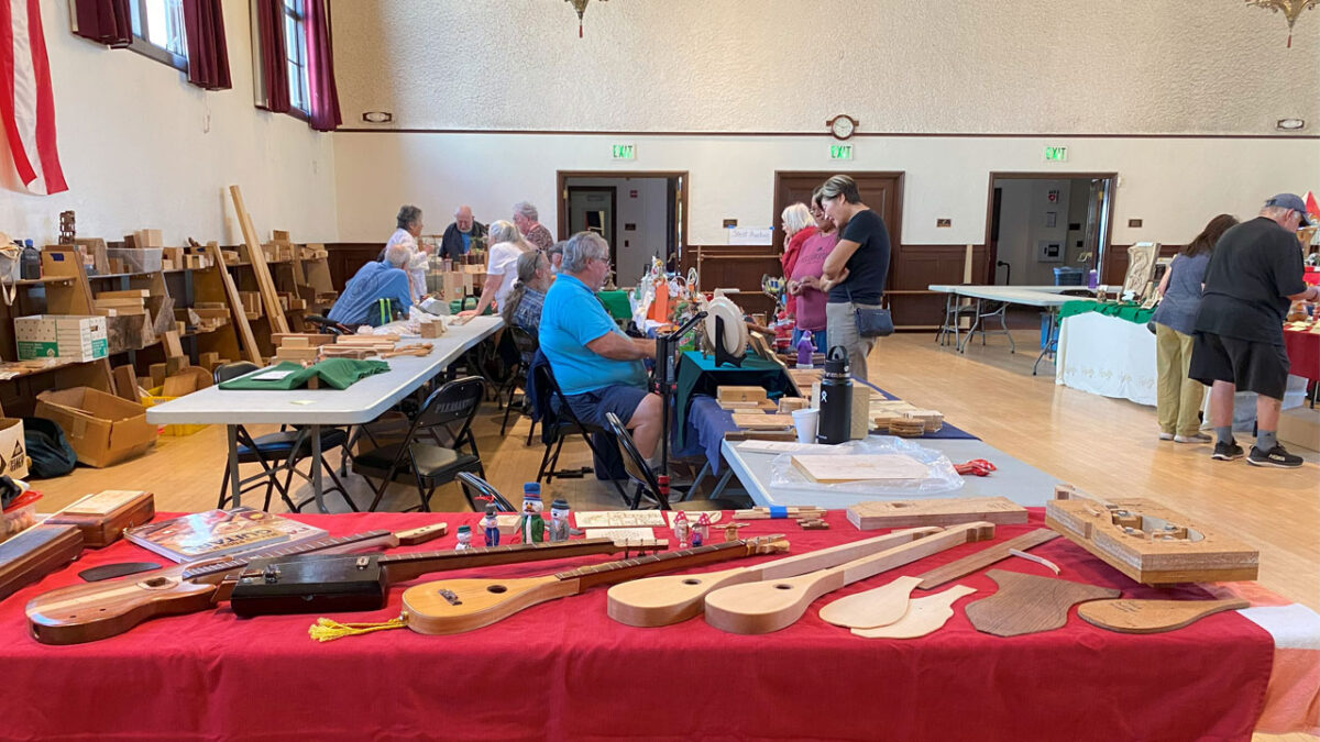 Woodcarving show visitors between tables with woodcarving projects.