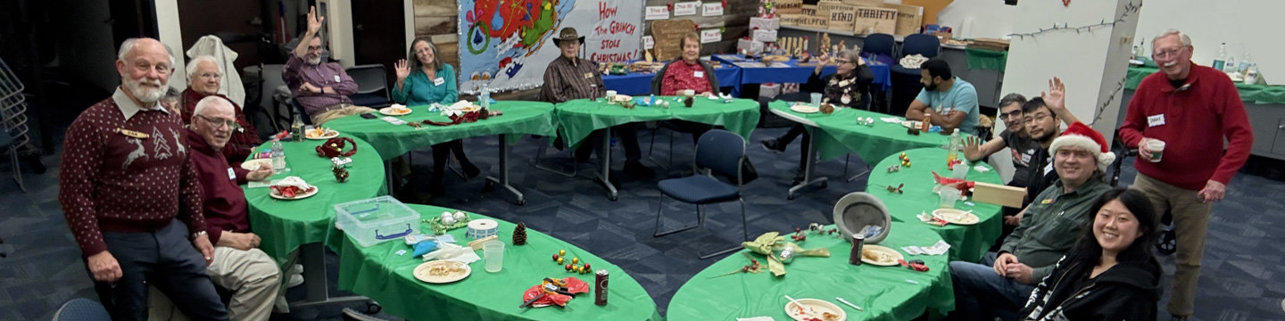 A dozen woodcarvers enjoy pizza while sitting at the oval tables.