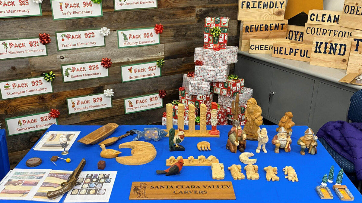 A woodcarving winter holiday display table with various handmade projects. A few feature steps of carving progression.