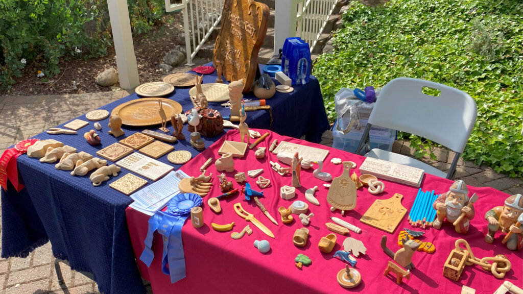 A display table with many woodcarving, whittling, and chip carving projects.