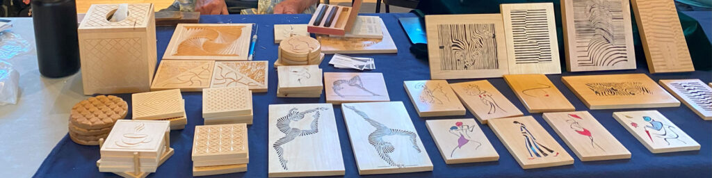 A table with dozens of chip carving panels and coasters carved by Ed Heskett, which he demonstrated at the 2025 TVC Woodcarving Show in Pleasanton, CA.