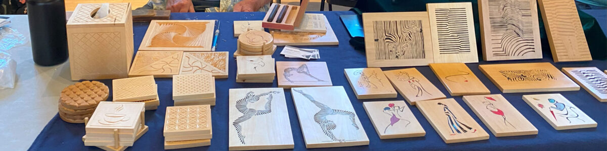A table with dozens of chip carving panels and coasters carved by Ed Heskett, which he demonstrated at the 2025 TVC Woodcarving Show in Pleasanton, CA.
