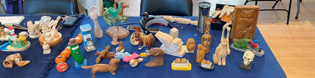 Jim Phipps filled his table with whittling projects at the 2025 TVC Woodcarving Show in Pleasanton, CA.
