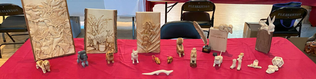 A table full of carved flowers and animals. Ngam Worley carved those and displayed them at the 2025 Tri-Valley Carvers woodcarving show.