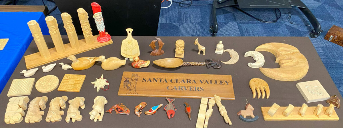 A table with dozens of woodcarving and whittling projects was displayed during woodcarving training for local scouts. Several projects show progression.