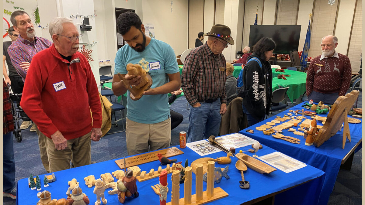 Woodcarvers discuss handmade projects on display.